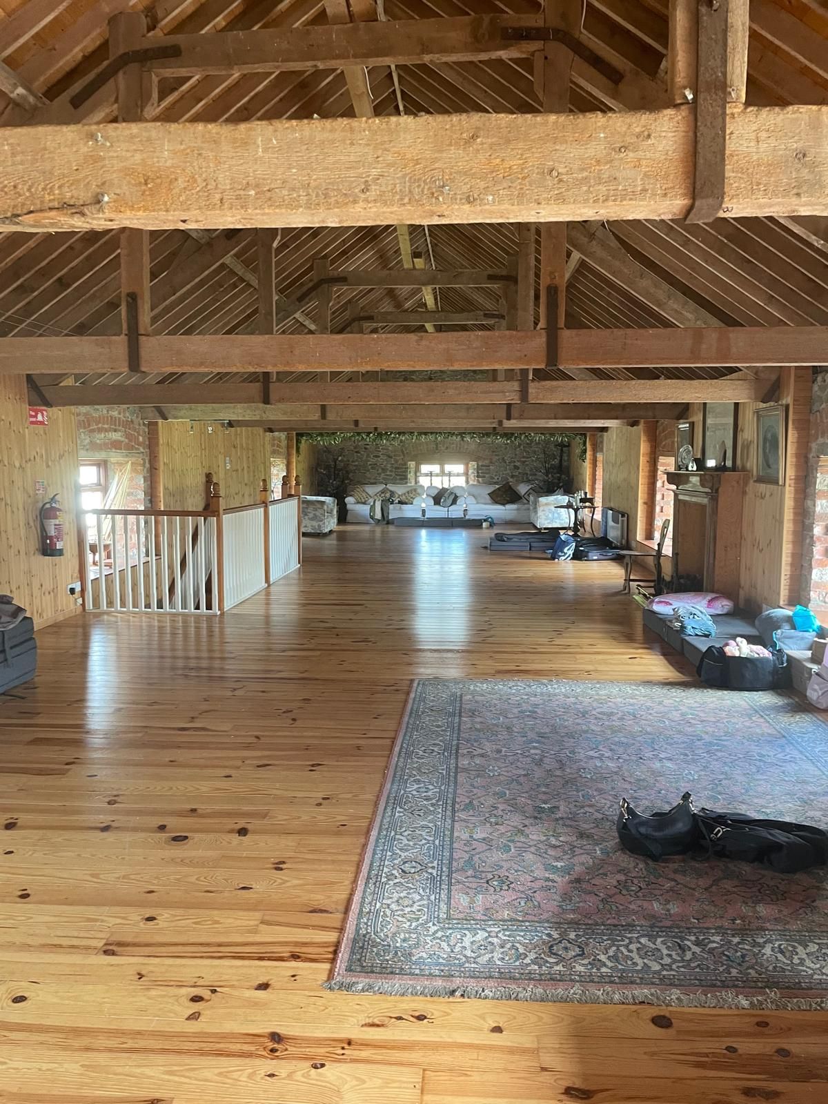 A large timber-beamed loft room with a rug and sofas