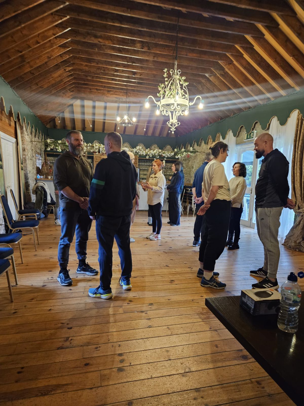 A group standing in a circle in a timber-ceilinged room