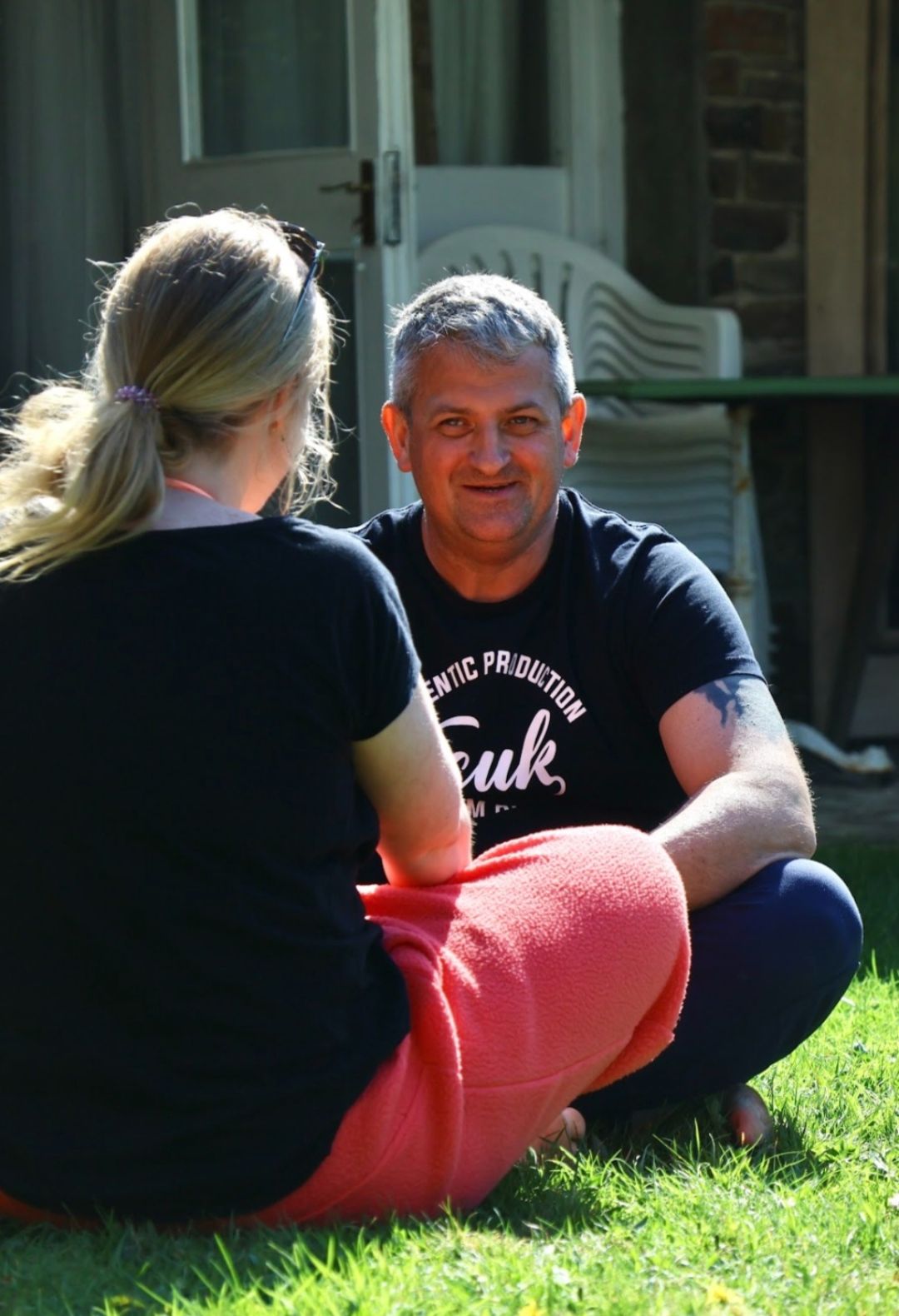 Two people sitting on the grass in conversation