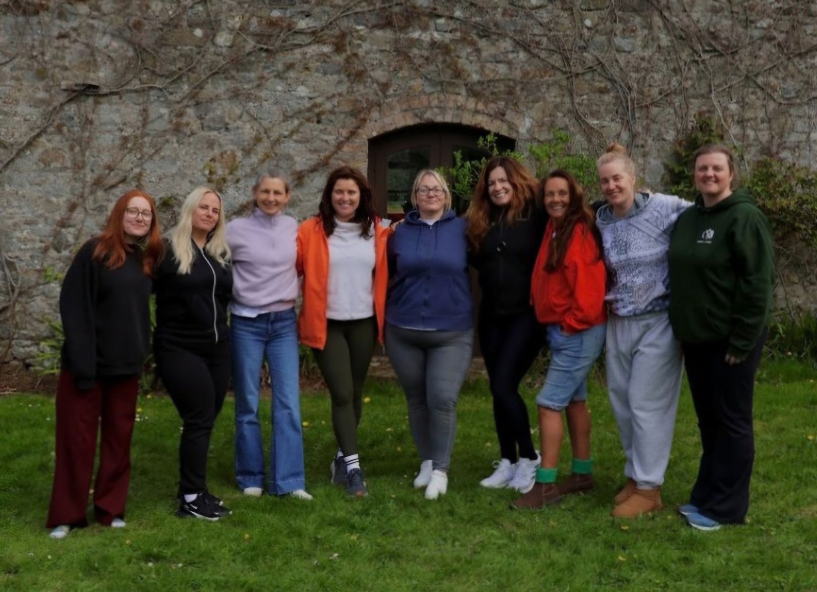 A group of retreat participants standing together in front of a stone wall